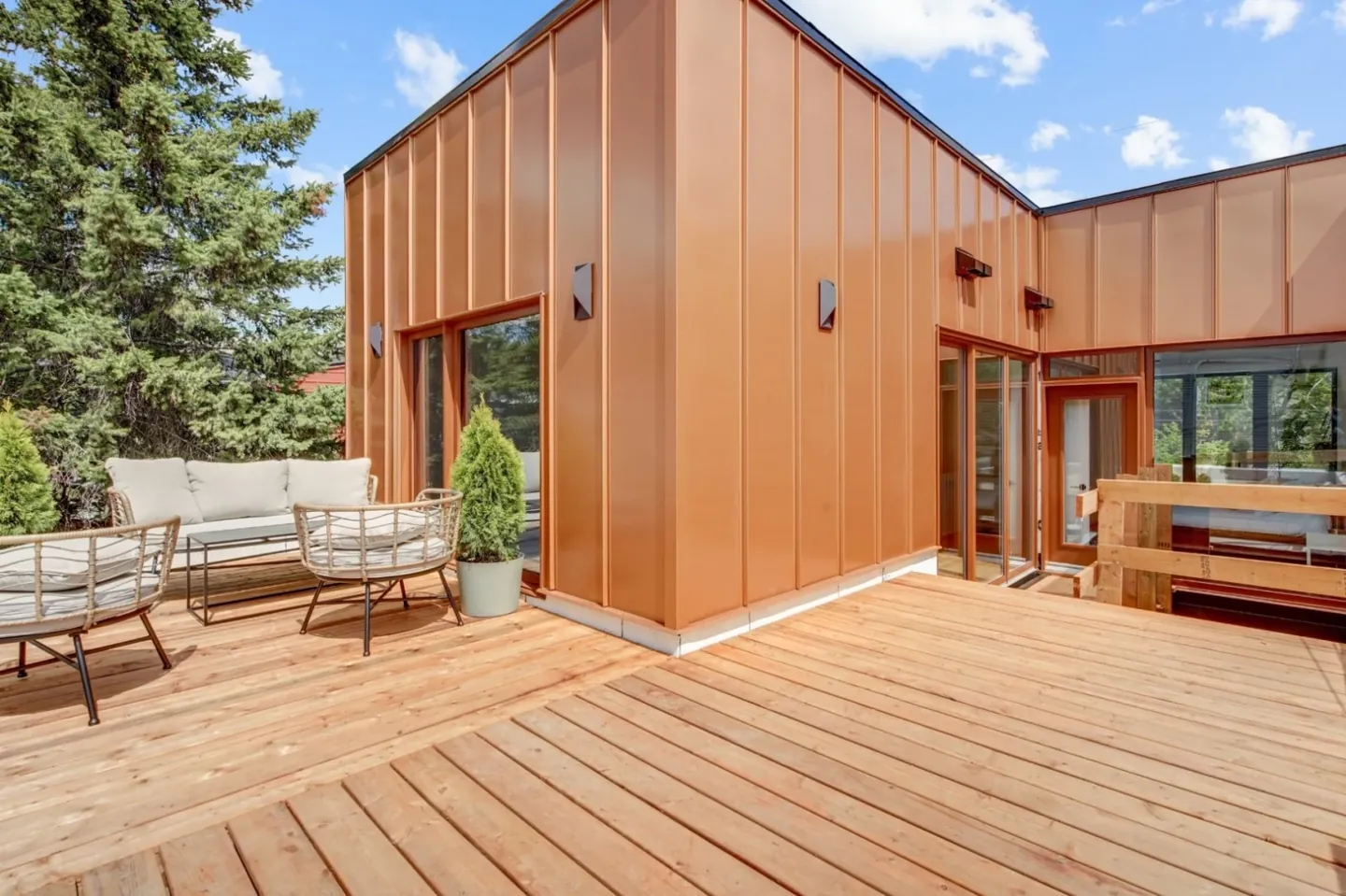 Terrasse en bois devant une maison au revêtement cuivré